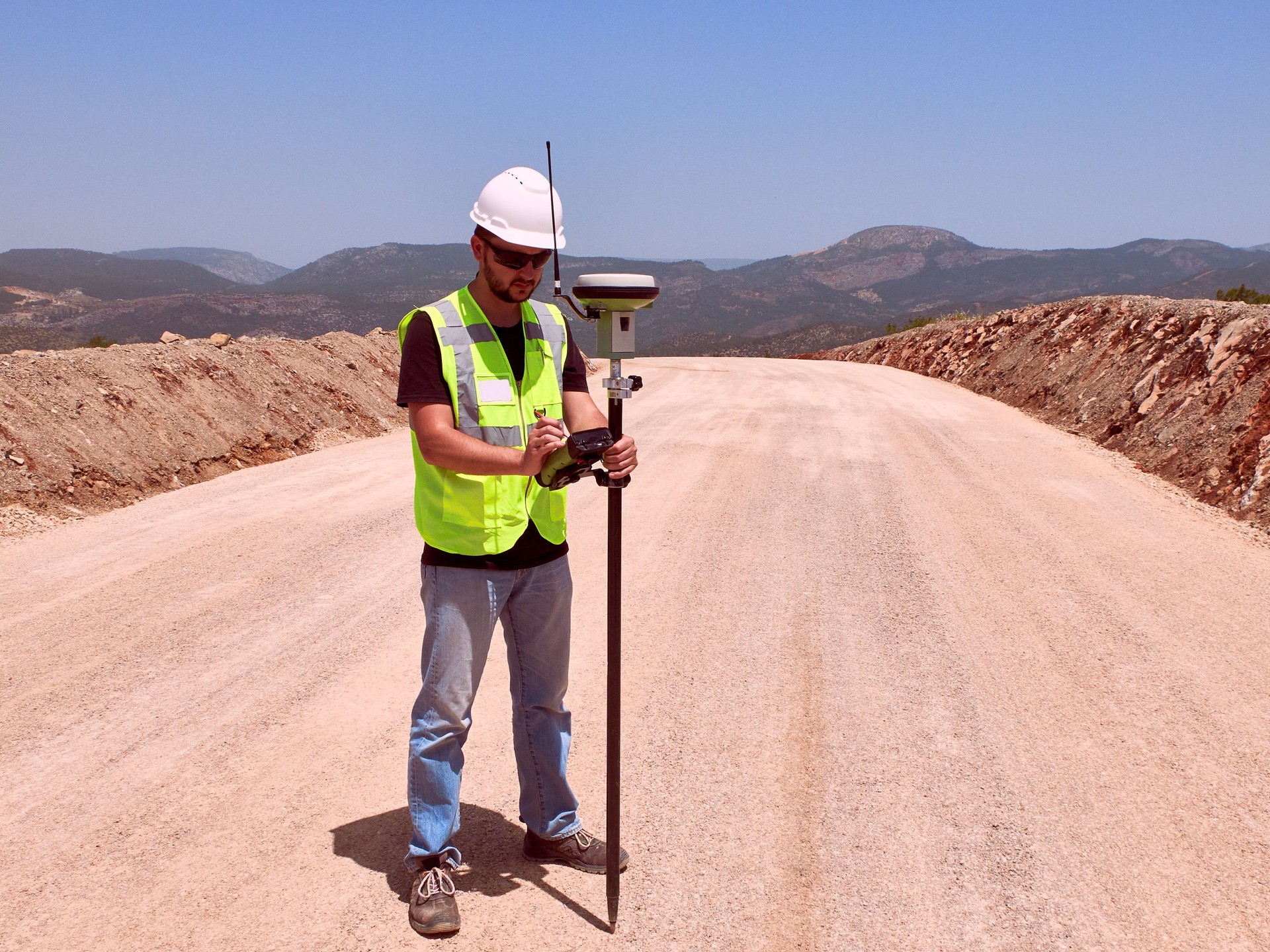 Geodetic engineer surveyor in white hard hat doing measurements with GNSS satellite receiver