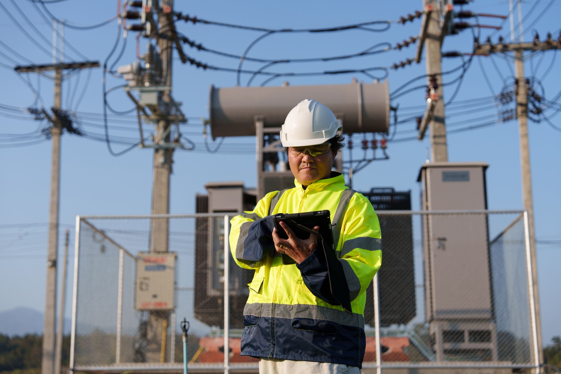 An expert engineer is inspecting a high-voltage transformer in a remote rural area.(Photo)